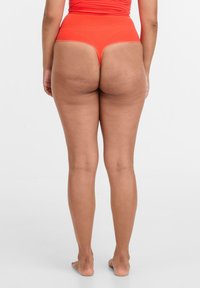 Hochgeschnittene, leuchtend orangefarbene Bikiniunterteile mit glatter Textur und minimalem Schnitt, die ein nahtloses Design und klare Linien aufweisen.