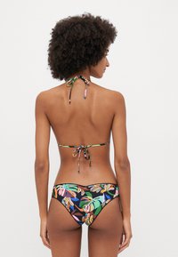 Black floral bikini with vibrant tropical patterns, featuring a halter neck tie, thin straps, and a medium-coverage bottom design.