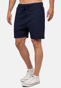 Costumi da bagno blu navy con vita elastica e coulisse. Tessuto morbido, tasche laterali e logo del brand ricamato in modo discreto sulla gamba.