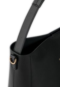 Black leather handbag with a smooth texture, featuring a structured shape, adjustable strap, and a gold-tone metal ring accent.