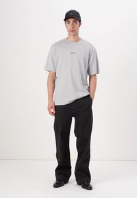 Tricou gri cu mânecă scurtă, cu logo-ul "BOSS", asortat cu pantaloni negri largi și pantofi negri, completat cu o șapcă neagră. Design simplu și lejer.