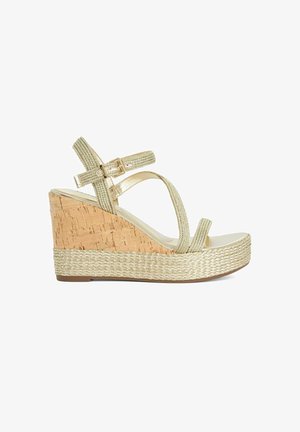 Keilsandalette mit Korkabsatz und geflochtenen, metallischen Riemen. Offen an der Zehenpartie und mit Knöchelschnalle. Hellbeige Farbe mit strukturierten Akzenten.