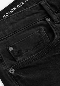 Zwarte denim jeans met een klassieke snit, voorzien van een klein achterzakje, zilverkleurige hardware en een gestructureerde stof. Nadruk op duurzaamheid en flexibiliteit.