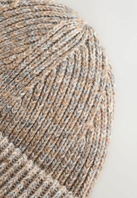 Knitted beanie in shades of tan, gray, and cream. Features a textured pattern with a rolled cuff. Made from soft, warm yarn.