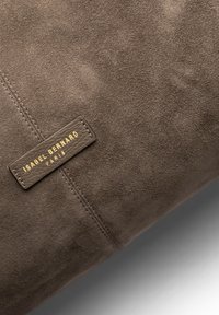 Bruine suède handtas met een gestikt naad en een rechthoekig leren label met "ISABEL BERNARD PARIS" in gouden letters.