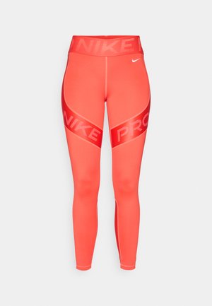 Koraalrode Nike Pro legging met hoge tailleband, witte Nike swoosh op de rechterheup en opvallende "NIKE PRO" tekst over de dijen.