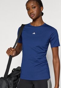 Camiseta deportiva azul marino con cuello redondo y mangas cortas, con un pequeño logo blanco en el pecho, hecha de un tejido elástico y que absorbe la humedad.