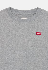 Siv sweatshirt z ribanim ovratnikom, ki ima na prsih majhen rdeč logo Levi's. Mehka tkanina iz mešanice bombaža, priložnostna in preprosta zasnova.