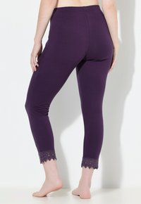 Fioletowe legginsy z miękkiego materiału, z falbanką z koronki przy kostce i gładkim, elastycznym pasem.