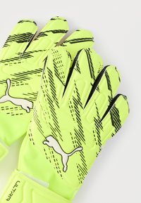 Puma målvaktshandskar i starkt gul färg med svarta diagonala ränder och texturerat grepp. Har vit logotyp och kardborreband för säker passform.
