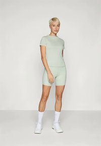 Lys grønn treningssett som inkluderer en tettsittende t-skjorte med korte ermer og matchende sykkelshorts. Laget av glatt, stretchy stoff med et strømlinjeformet design.