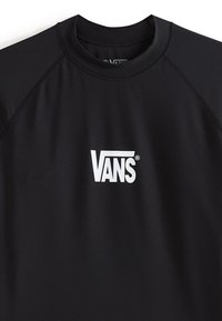 Top anti-éruption noir en matériau extensible avec un logo Vans blanc à l'avant, doté d'un col arrondi et de manches raglan.