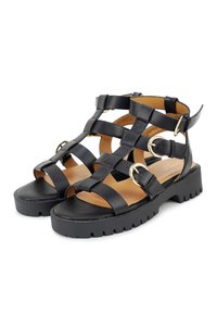 Schwarze Leder-Sandalen mit mehreren verflochtenen Riemen, goldenen Akzenten, klobigen Sohlen und einem strukturierten Muster für zusätzlichen Halt und Haltbarkeit.