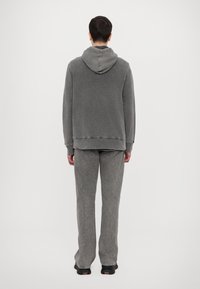 Grauer Kapuzenpullover mit Kordelzug und gerippten Bündchen, kombiniert mit passenden grauen strukturierten Hosen. Lässige Passform mit weichem Finish.