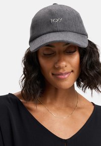 Casquette en velours côtelé gris avec une visière incurvée et un logo Roxy brodé. Elle possède une texture douce et un design classique à six panneaux.