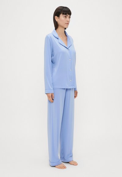Conjunto de pijama em seda azul claro com mangas longas, fecho de correr e calças combinando. Apresenta um colarinho de notch e um corte relaxado para maior conforto.