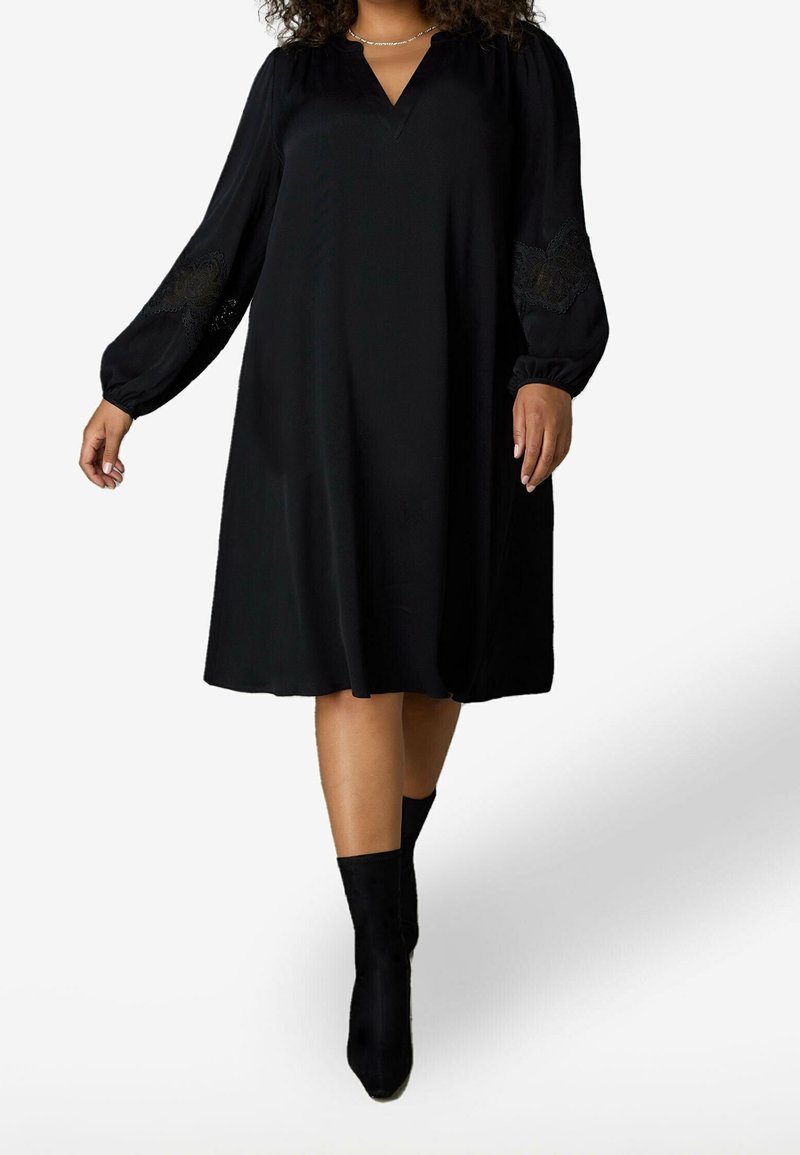 Černé áčkové šaty s dlouhými volnými rukávy, výstřihem do V a krajkovými akcenty na rukávech. Hladký materiál s volným střihem pro pohodlí.