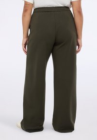 Olivgröna vida byxor i mjukt tyg med en rynkad elastisk midja, som har en jämn yta och inga synliga mönster.