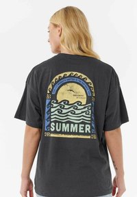 T-shirt in cotone nero con un vivace design grafico sulla schiena, che include onde e sole, con la scritta "ESTATE" ben in evidenza.