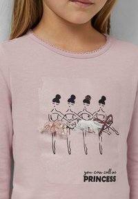 Helles rosa Langarmshirt mit einem Druckmotiv von vier Balletttänzerinnen, verziert mit gestuften Tüll und Pailletten sowie schwarzem Text.