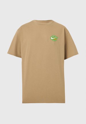 Béžové tričko s krátkym rukávom s malým zeleno-bielym kruhovým logom na ľavej strane hrudníka, ktoré obsahuje znak swoosh a text.