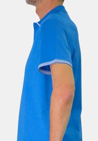 Polo blu con colletto e accenti a righe sui polsini, realizzato in tessuto morbido. Presenta un design a vestibilità slim.