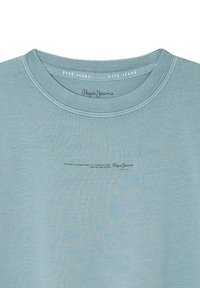 Camiseta de algodón azul claro con cuello redondo, que presenta un logotipo de texto en la parte frontal y una textura suave. Diseño simple sin patrones.