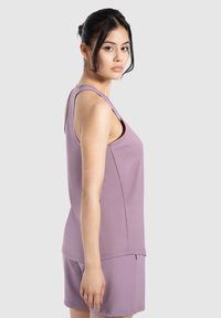 Top senza maniche di un viola chiaro con scollo rotondo, abbinato a pantaloni corti dello stesso colore. Tessuto liscio; vestibilità comoda; dettagli minimi.