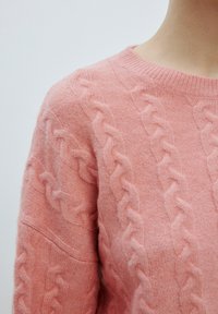 Rosa gestrickter Pullover mit einem Kabelstrickmuster, Rundhalsausschnitt und weicher Textur. Eine Nahaufnahme zeigt die Details an den Ärmeln und am Körper.