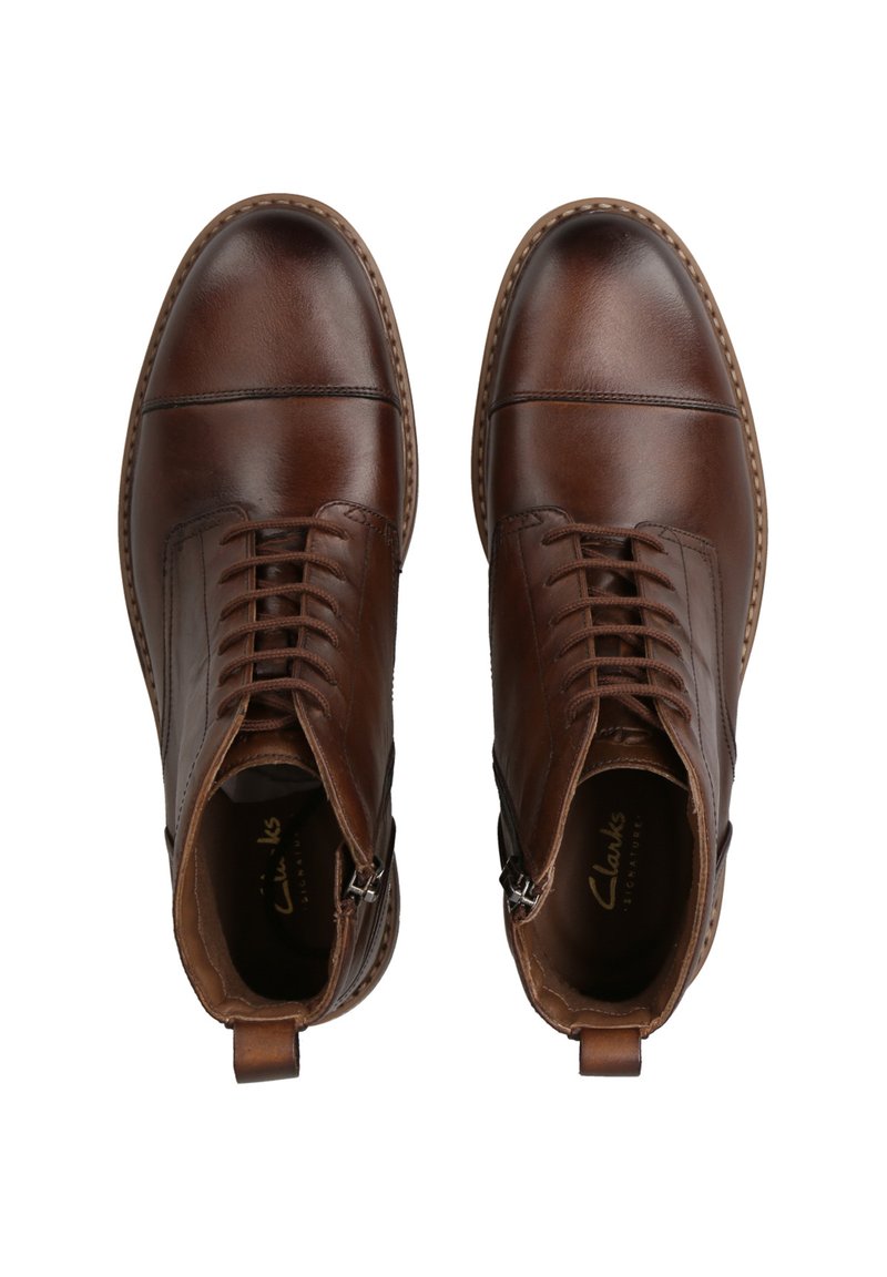 Braune Leder-Ankle-Boots mit runder Zehenpartie, Schnürung vorne und seitlichem Reißverschluss. Mit subtiler Naht und strukturiertem Finish.