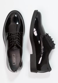Chaussures habillées en cuir verni noir avec un bout rond, un laçage et une semelle en caoutchouc noire unie. Finition lisse et brillante, accents minimaux.