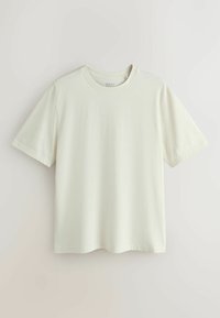 T-shirt uni blanc cassé à manches courtes avec col rond et coupe décontractée, présenté sur un fond clair neutre.