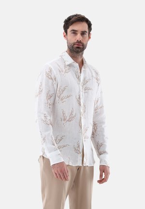 Langes, weißes Leinenhemd mit beigen botanischen Mustern, mit Knopfkragen und umgeschlagenen Ärmeln. Glatte, leichte Textur.
