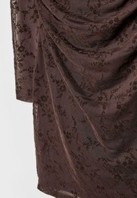 Brązowa tkanina z drapowaniem, zdobiona skomplikowanym haftem kwiatowym i fakturą, z delikatnym połyskiem oraz płynnie zaprojektowanymi elementami.