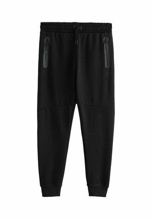 Pantalones de chándal negros con cintura elástica, cordón y dos bolsillos con cremallera. Presenta una textura suave y un diseño ajustado.