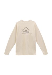 Långärmad cremefärgad topp i texturerat tyg med rund halsringning, med ett triangulärt grafiskt tryck: "HALO OFF DUTY GEAR HIGH ALTITUDE LOW OPENING."