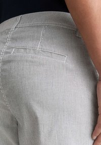 Pantalon en coton rayé présentant de fines lignes verticales grises et blanches, avec une poche arrière et une texture de tissu lisse.