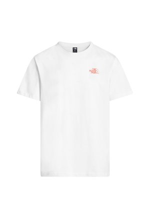 Młoda osoba nosząca beżową czapkę, białą koszulkę z czerwono-żółtym kwiatowym szkicem i napisem "The North Face" na plecach, do tego pomarańczowe szorty.