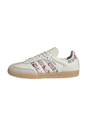 Baskets Adidas Samba blanches avec des bandes et un renfort de talon à motif floral, semelle en gomme et bout en daim.