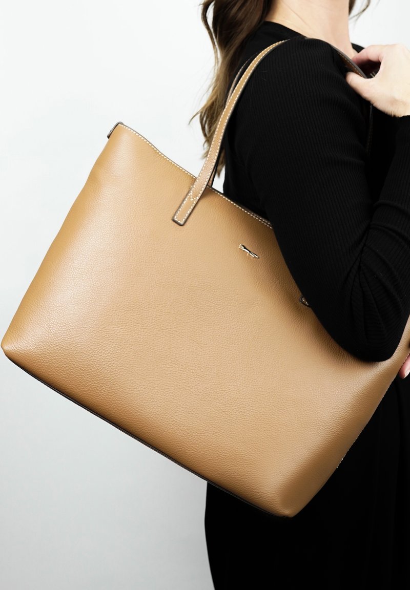 Leren totebag in bruin met een gladde textuur, rechthoekige vorm, twee schouderriemen en een zilveren logo-detail aan de voorkant.