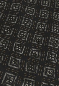 Černá tkanina s geometrickým vzorem čtverců a hvězd, doplněná bílými a béžovými pruhy, vytvářející strukturovaný vzhled.