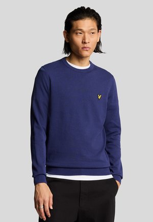 Maglione in maglia blu navy con collo rotondo, polsini e orlo ribattezzati, caratterizzato da un piccolo logo giallo sul lato sinistro del petto. Texture liscia.