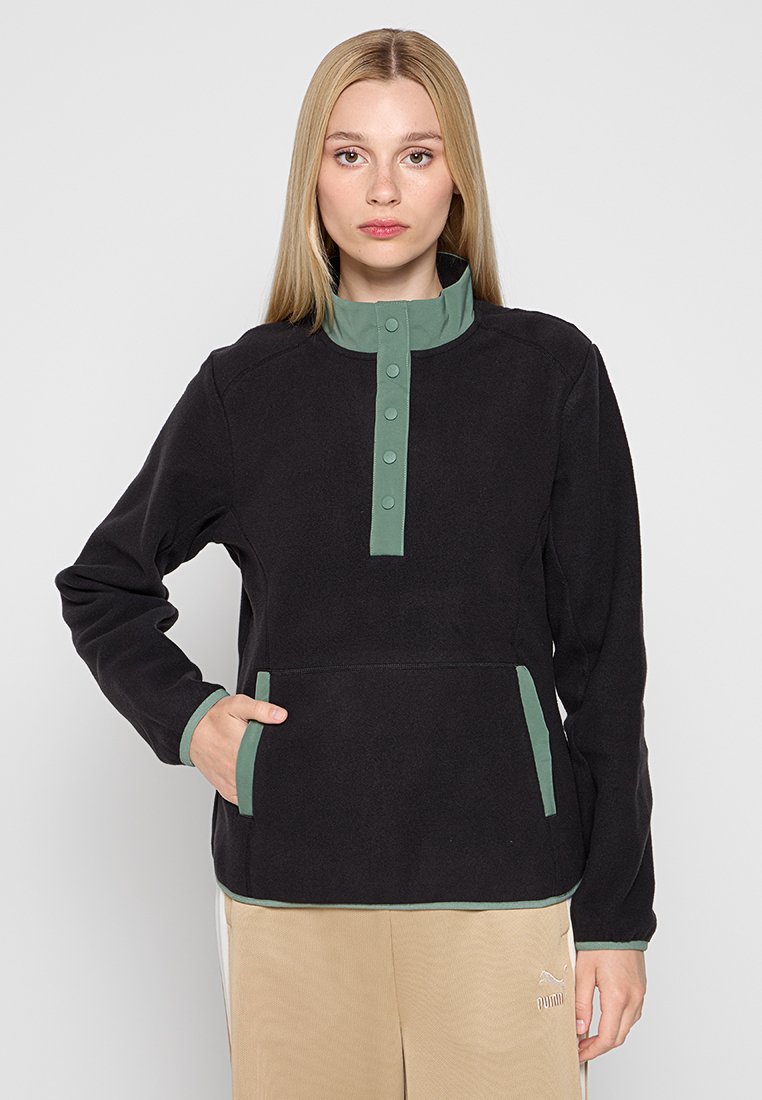 Zwart fleece pullover met een groene drukknoopkraag, zijzakken en contrasterende accentuering op de mouwen. Zachte textuur en gestructureerde vorm.