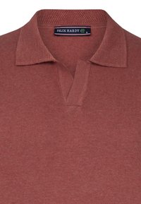 Polo de punto rojo con un collar texturizado, que presenta un medio botón y una etiqueta cosida en el interior del collar. Tejido suave y diseño casual.