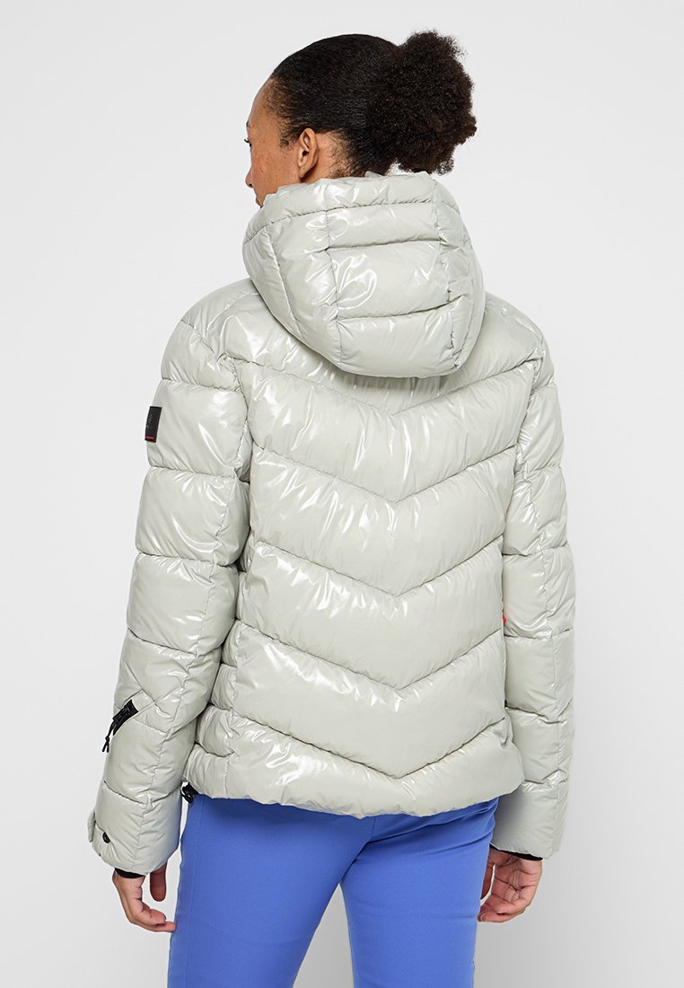 Hellgraue, glänzende Pufferjacke mit Kapuze. Verfügt über ein Chevron-Muster, Reißverschlusstaschen und elastische Bündchen. Rückansicht.
