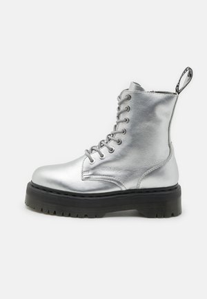 Silver metallic ankle boot with lace-up design, thick black sole, and a pull tab at the heel. Smooth texture with rounded toe shape.