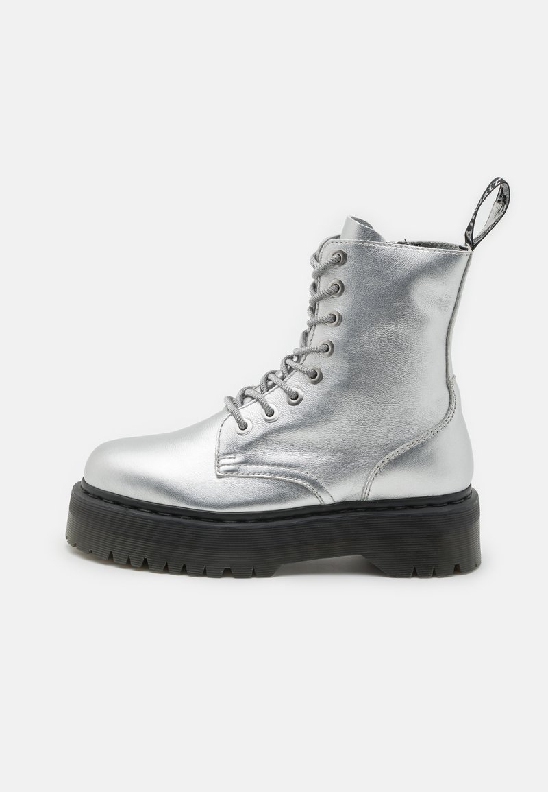 Stivaletto ankle in metallo argento con design a lacci, suola nera spessa e linguetta sul tallone. Texture liscia con forma della punta arrotondata.