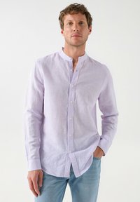 Camisa de manga larga en lavanda claro con un cuello mandarín abotonado, textura sutil y un pequeño logo bordado en el lado izquierdo del pecho.