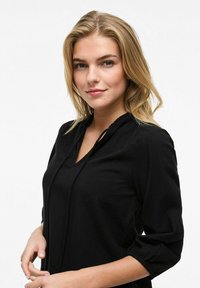 Blusa nera con scollatura a V, maniche arricciate e una texture morbida. Design semplice, stile aderente e vestibilità morbida intorno alla vita.