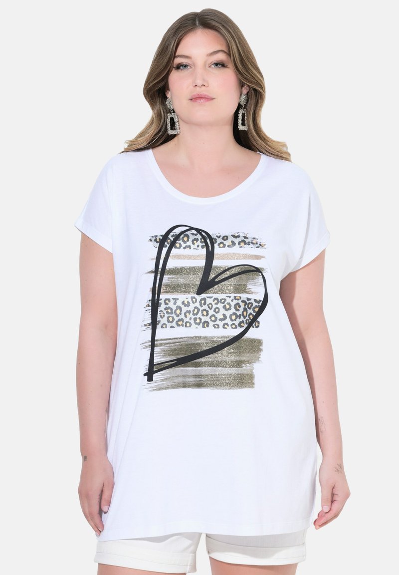 Vitt bomullströja med en svart hjärtformad kontur, guld- och leopardtrycksränder. Korta ärmar, avslappnad passform och rundad halsringning.